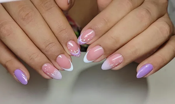 Diseño de uñas rosadas y lilas con detalles blancos